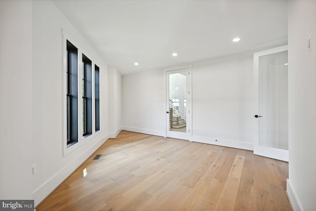 spare room featuring light wood-type flooring, visible vents, baseboards, and recessed lighting