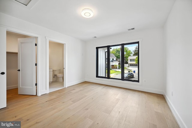 empty room featuring light wood-type flooring, visible vents, and baseboards