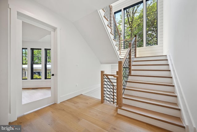 stairs with lofted ceiling, baseboards, and wood finished floors