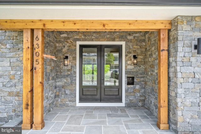 view of exterior entry featuring stone siding and french doors