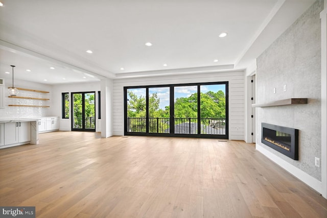 unfurnished living room with a large fireplace, light wood-type flooring, and recessed lighting