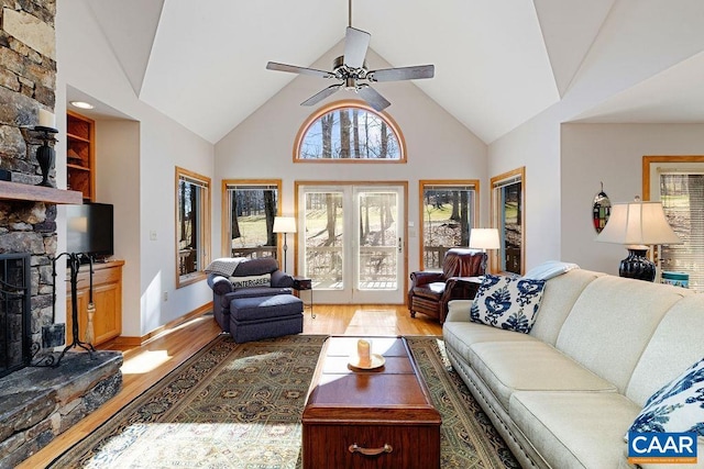 living room with ceiling fan, high vaulted ceiling, light wood-type flooring, and a fireplace