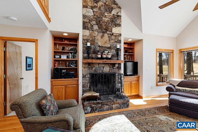 living room featuring ceiling fan, high vaulted ceiling, a fireplace, wood-type flooring, and built in shelves