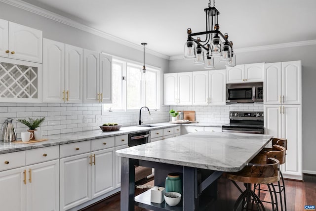 kitchen with white cabinets, hanging light fixtures, a center island, stainless steel appliances, and light stone countertops