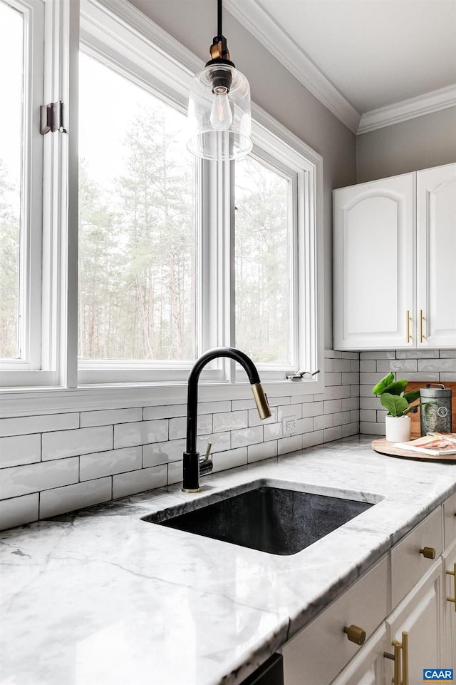 details with sink, ornamental molding, light stone countertops, and white cabinets