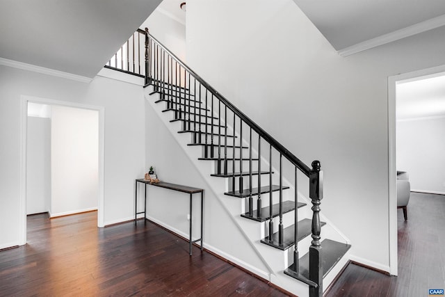 stairway featuring crown molding, wood-type flooring, and a towering ceiling