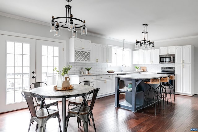 kitchen with french doors, white cabinetry, a center island, appliances with stainless steel finishes, and pendant lighting