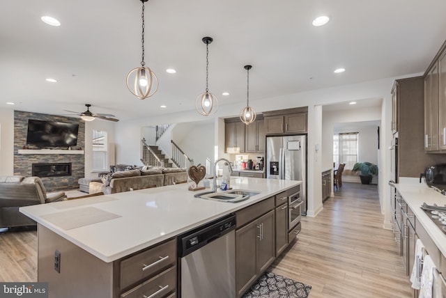 kitchen featuring dark brown cabinetry, open floor plan, appliances with stainless steel finishes, and a sink