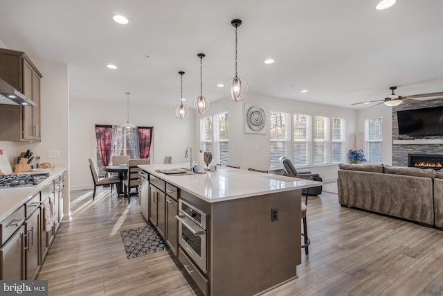 kitchen featuring light wood-style flooring, recessed lighting, a sink, appliances with stainless steel finishes, and open floor plan