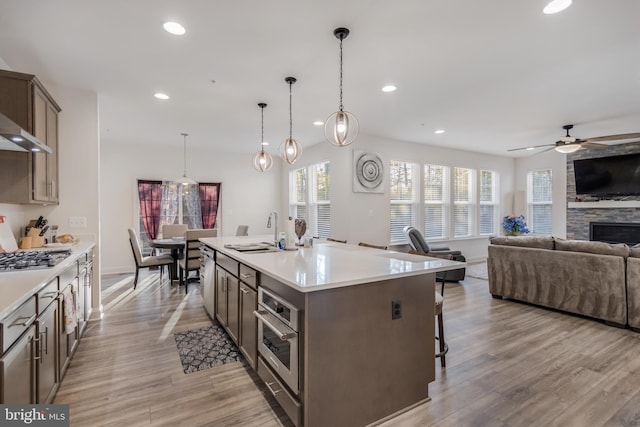 kitchen with open floor plan, light wood-type flooring, stainless steel appliances, and a sink