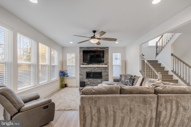 living room with stairway, baseboards, light wood finished floors, recessed lighting, and a stone fireplace