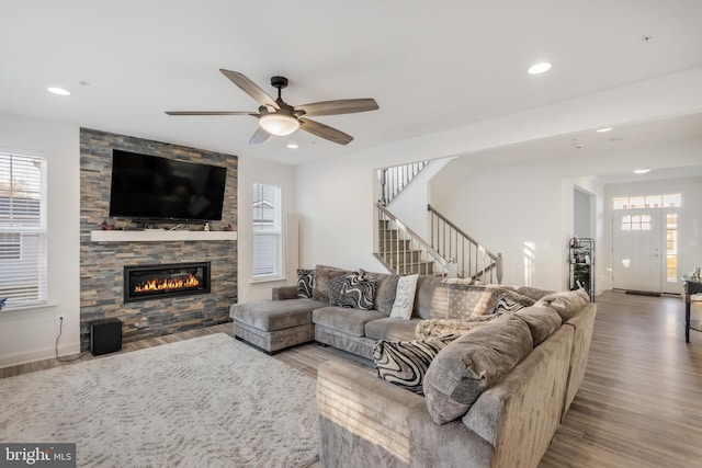 living area with recessed lighting, a fireplace, stairs, and wood finished floors