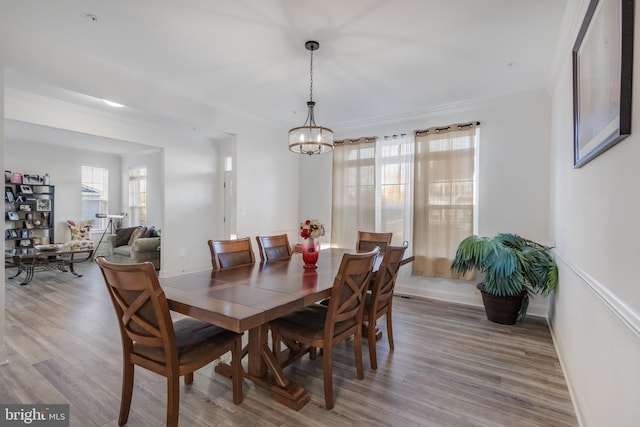 dining area with an inviting chandelier, crown molding, baseboards, and wood finished floors