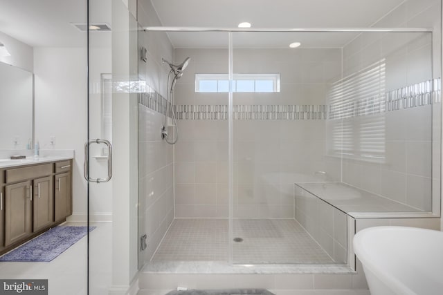 bathroom with visible vents, a stall shower, vanity, and a freestanding tub