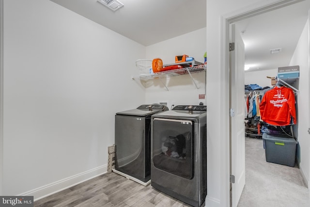 clothes washing area with visible vents, baseboards, laundry area, wood finished floors, and washer and dryer