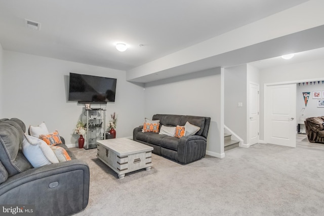 living area with visible vents, light carpet, baseboards, and stairway