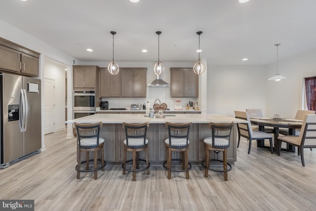 kitchen with a breakfast bar, appliances with stainless steel finishes, light wood-style flooring, and light countertops