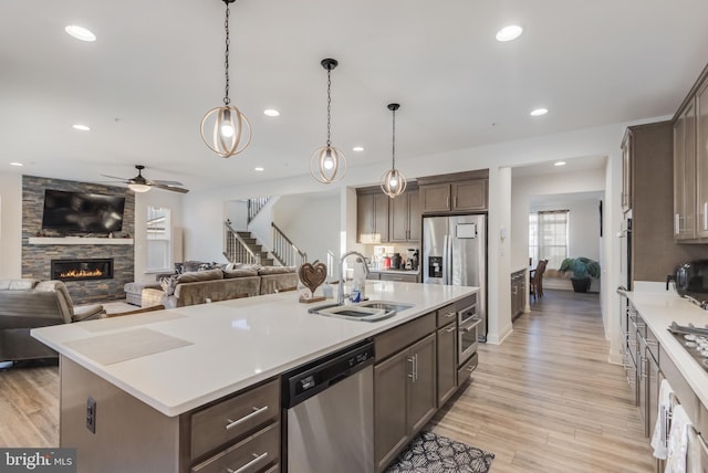 kitchen featuring a sink, appliances with stainless steel finishes, open floor plan, and dark brown cabinets