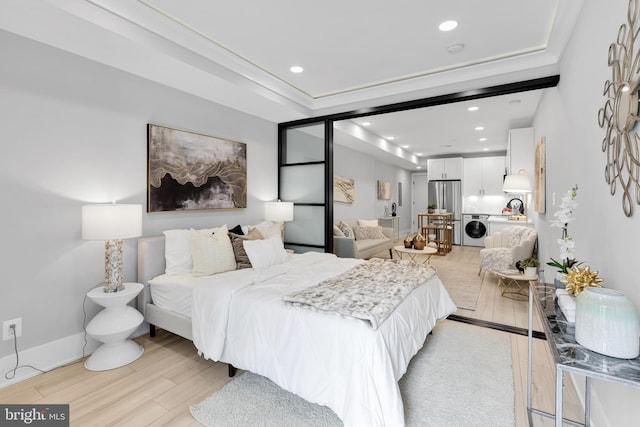 bedroom with ornamental molding, a tray ceiling, stainless steel fridge, and light hardwood / wood-style flooring