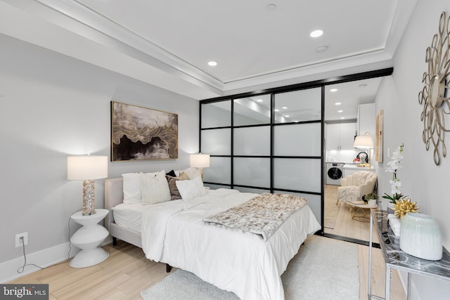 bedroom featuring washer / clothes dryer, crown molding, and light wood-type flooring