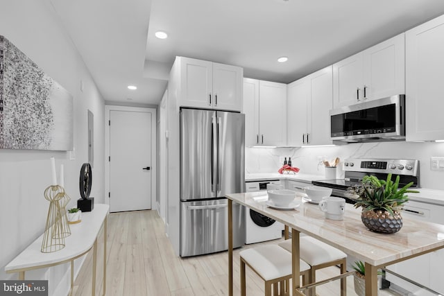 kitchen featuring white cabinetry, light hardwood / wood-style flooring, stainless steel appliances, and tasteful backsplash