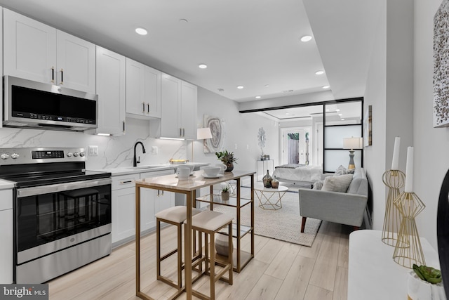 kitchen with appliances with stainless steel finishes, sink, decorative backsplash, and white cabinets