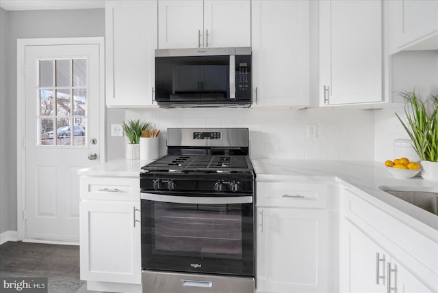 kitchen with stainless steel appliances, white cabinets, and backsplash