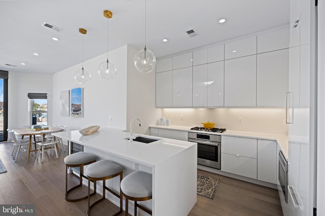 kitchen with white cabinetry, a kitchen bar, appliances with stainless steel finishes, and sink