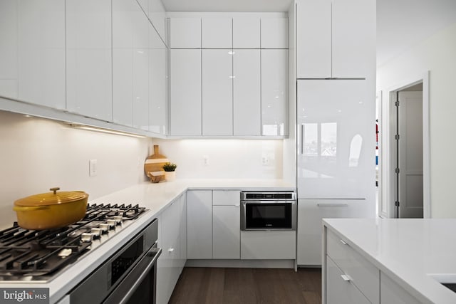 kitchen with oven, white cabinetry, dark hardwood / wood-style flooring, and cooktop