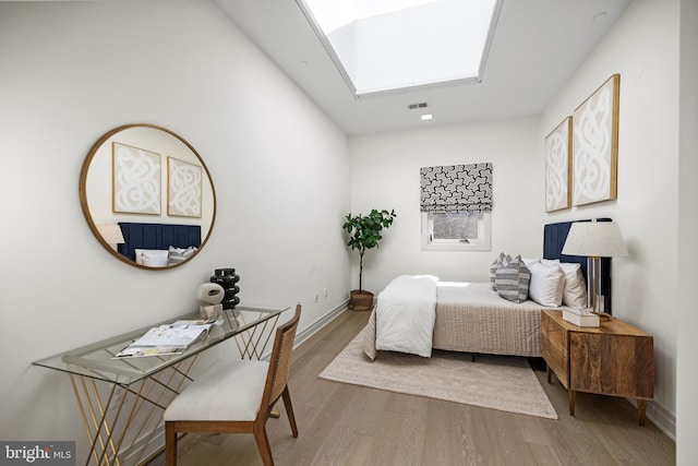 bedroom with a skylight and hardwood / wood-style floors