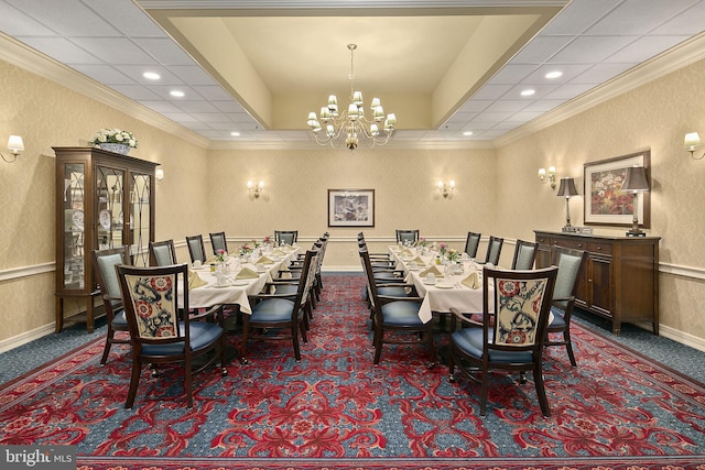 carpeted dining space with a drop ceiling, a notable chandelier, and ornamental molding