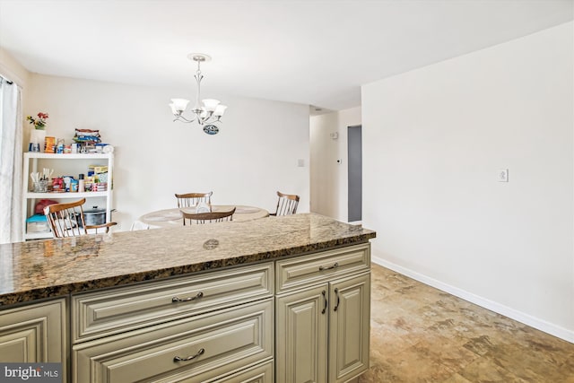 kitchen featuring dark stone countertops, hanging light fixtures, cream cabinets, and a chandelier