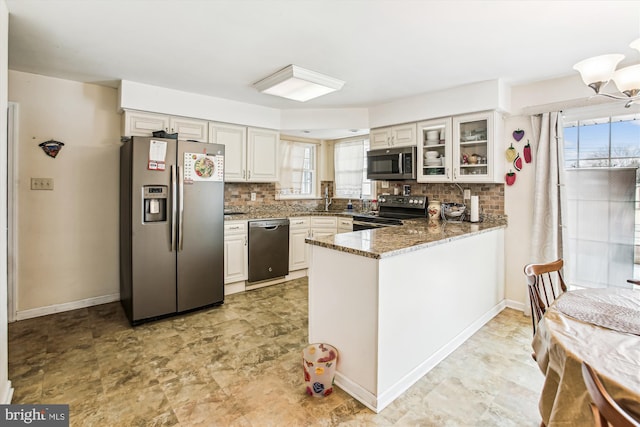 kitchen featuring appliances with stainless steel finishes, tasteful backsplash, white cabinets, dark stone counters, and kitchen peninsula