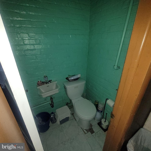 bathroom with brick wall and toilet