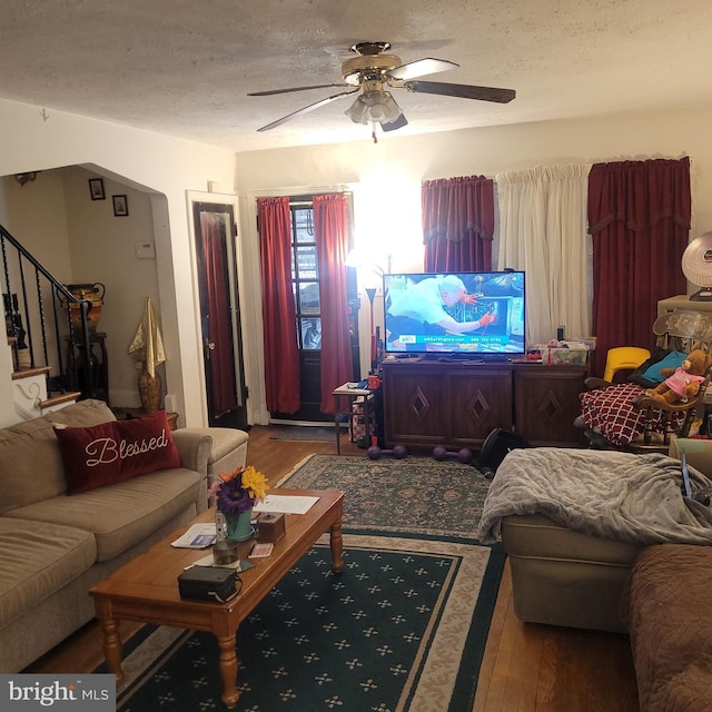 living room featuring ceiling fan, hardwood / wood-style floors, and a textured ceiling