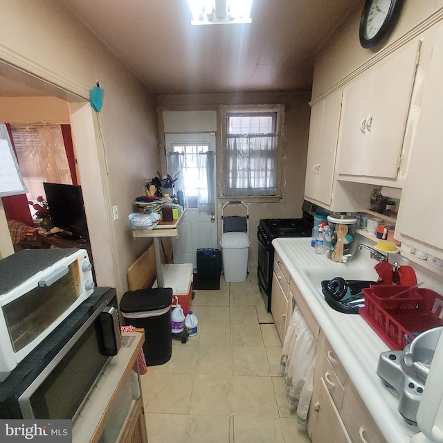 kitchen with black gas range, light tile patterned floors, and sink