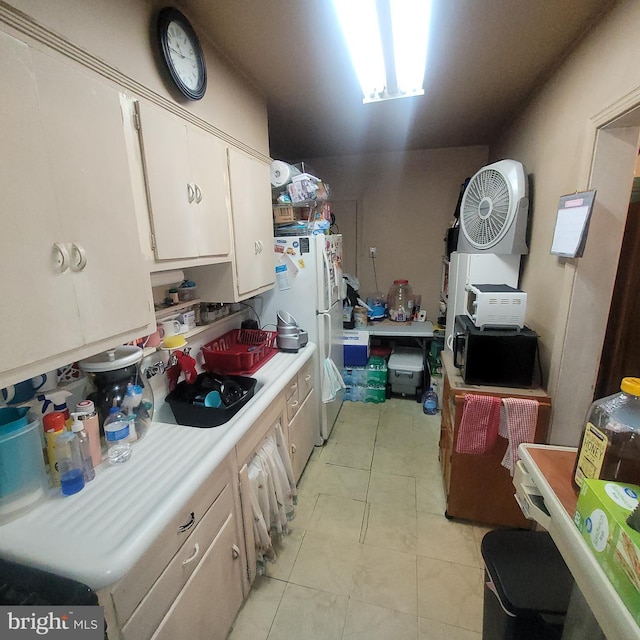 kitchen featuring sink, light tile patterned floors, white fridge, and white cabinets