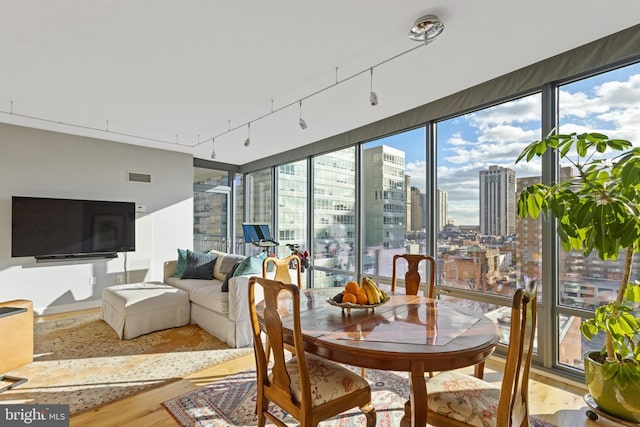 sunroom featuring rail lighting, visible vents, and a city view