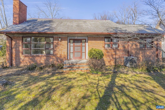 rear view of property with a yard and central AC