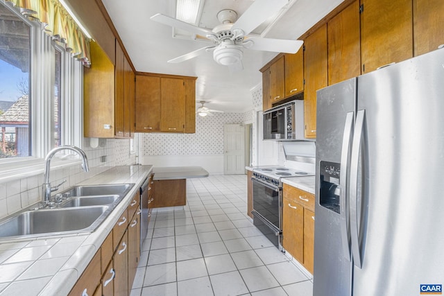 kitchen featuring sink, tile countertops, light tile patterned floors, ceiling fan, and stainless steel appliances