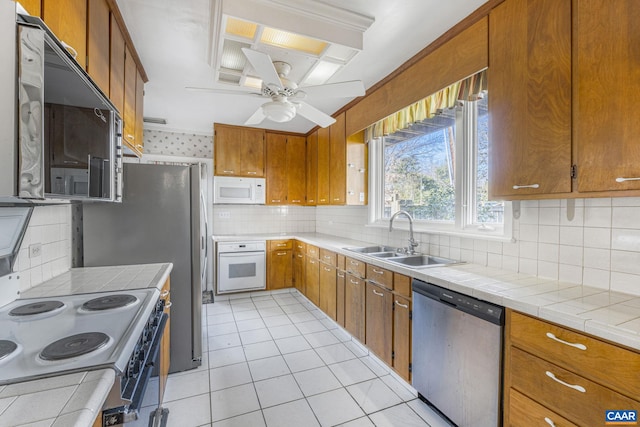 kitchen featuring stainless steel appliances, sink, tile counters, and backsplash