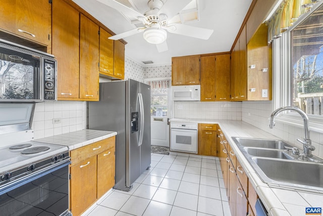 kitchen with light tile patterned flooring, white appliances, tile countertops, and sink