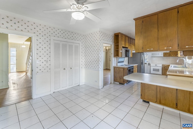 kitchen featuring stainless steel appliances, ornamental molding, sink, and light tile patterned floors