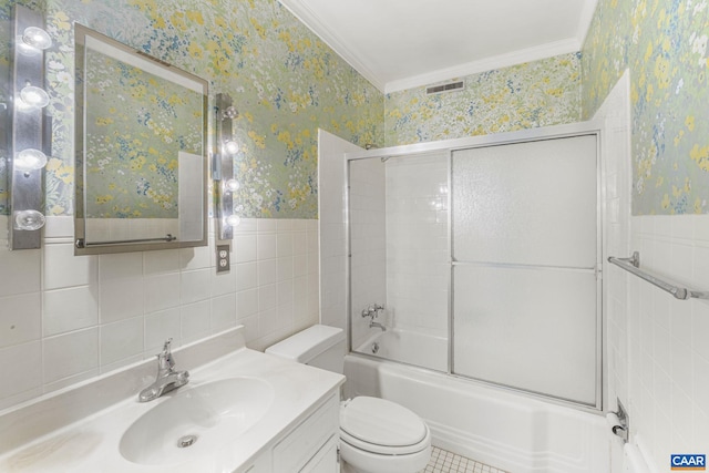 full bathroom with tile walls, shower / bath combination with glass door, ornamental molding, vanity, and toilet