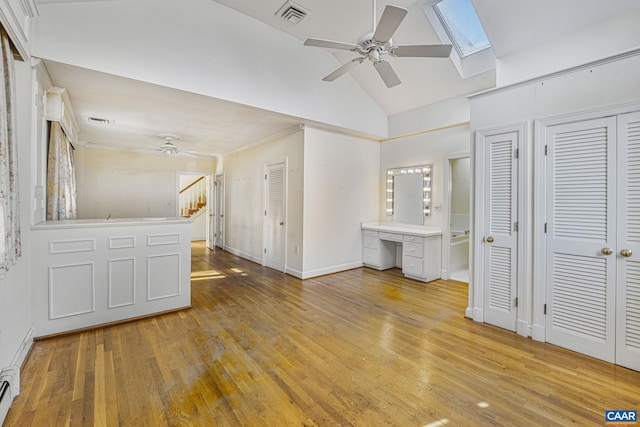 unfurnished bedroom featuring connected bathroom, a skylight, multiple closets, ceiling fan, and light hardwood / wood-style floors