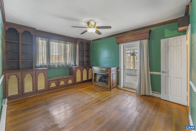 unfurnished living room with hardwood / wood-style flooring, ceiling fan, and crown molding