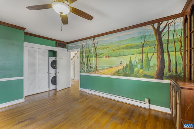 unfurnished bedroom with a baseboard radiator, ornamental molding, stacked washer and clothes dryer, and wood-type flooring