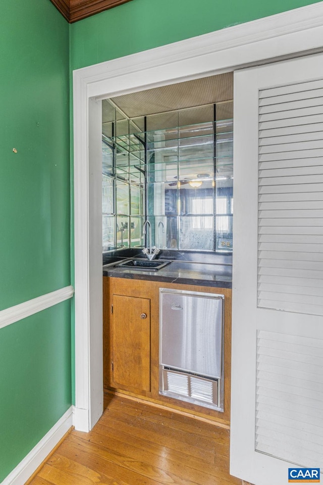 bar featuring dishwasher, sink, and light hardwood / wood-style flooring