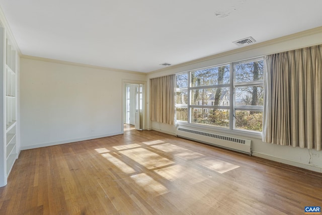 spare room with ornamental molding, radiator heating unit, and light hardwood / wood-style floors