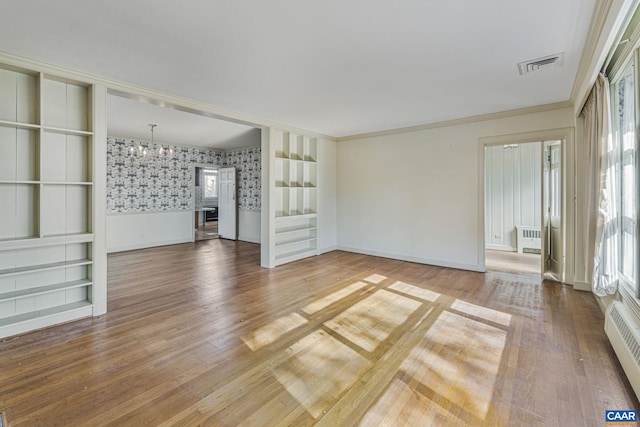 unfurnished living room with hardwood / wood-style floors, a healthy amount of sunlight, a baseboard heating unit, and radiator heating unit